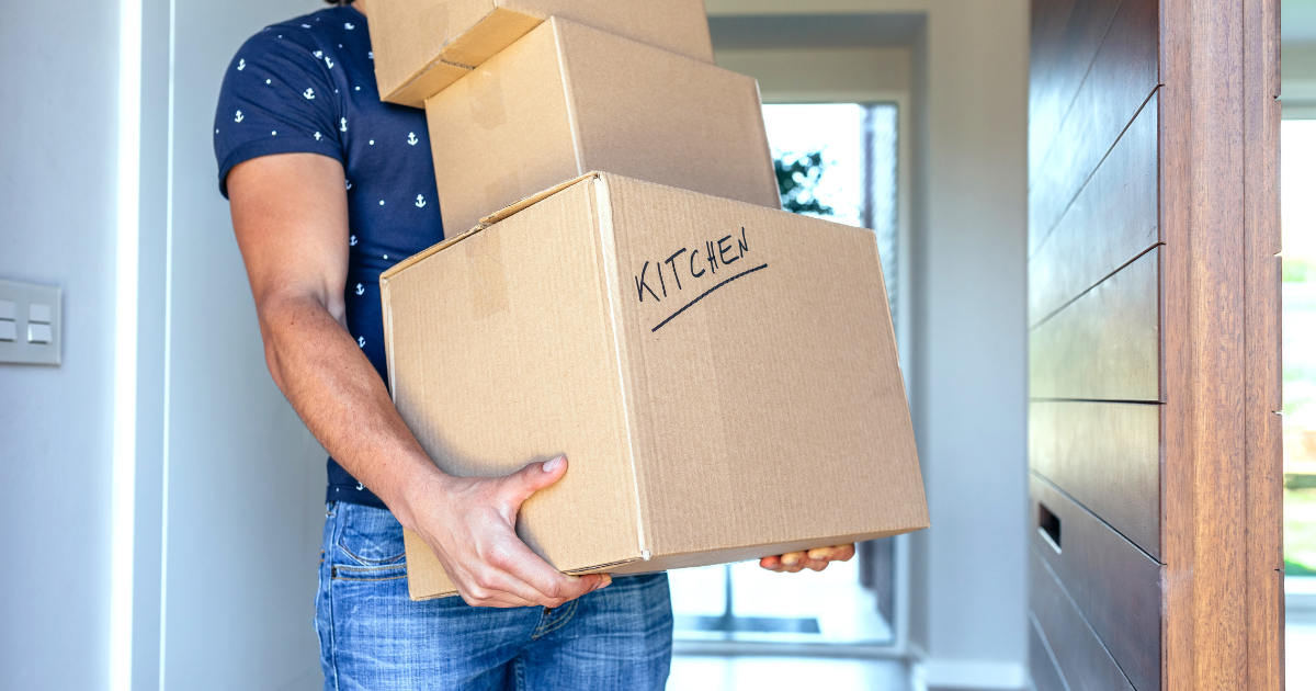 Man carrying moving boxes, one is marked kitchen